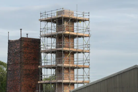Scaffolding around a tall brick chimney
